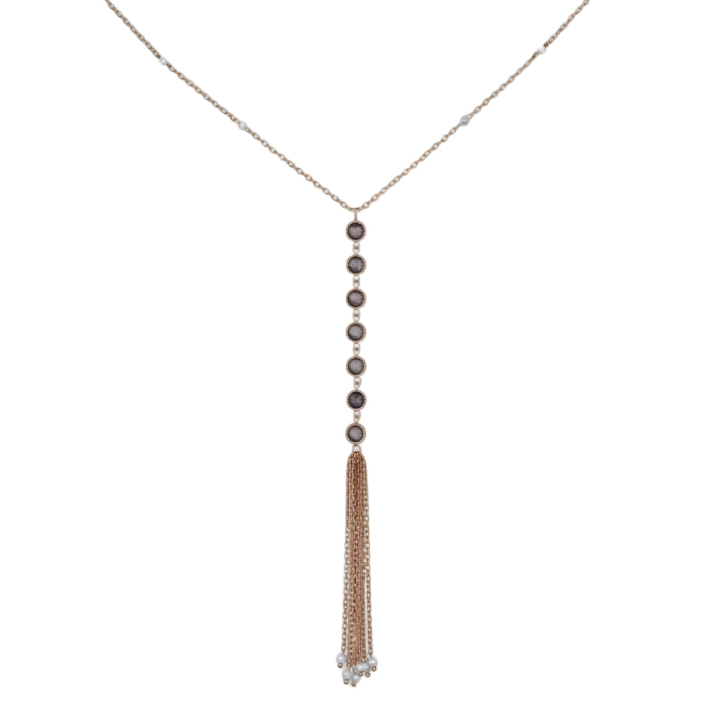 Gold necklace with tassel on a light gray background